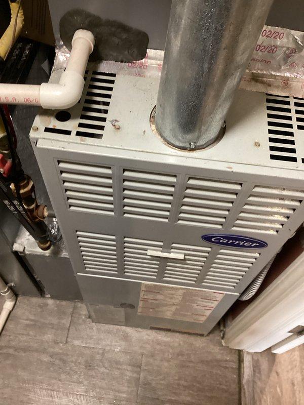 Completed comprehensive HVAC system assessment for furnace replacement estimate at residential property. Documented existing Carrier furnace unit, associated ductwork, venting systems including PVC condensate drainage, and metal flue pipe configuration. Photographed current equipment condition showing age-related wear, discoloration on ductwork and flue components, and overall mechanical room layout to provide accurate replacement specifications and scope of work for property management approval.