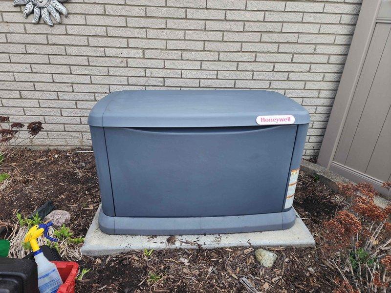 Completed scheduled maintenance inspection on Honeywell standby generator unit. Performed visual inspection of exterior housing, verified proper mounting on concrete pad, opened access panel to inspect internal components including engine, electrical connections, and control systems. All components found clean and in good operating condition with no signs of wear, damage, or debris accumulation requiring attention.