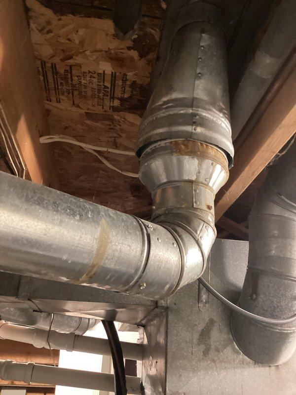 Responded to service call for leaking water heater. Upon inspection, found residential gas-fired water heater showing signs of age with visible corrosion and active leak requiring replacement. Documented existing installation including ductwork configuration in ceiling space and current water heater setup with gas line, plumbing connections, and venting system. Provided estimate for complete water heater replacement.