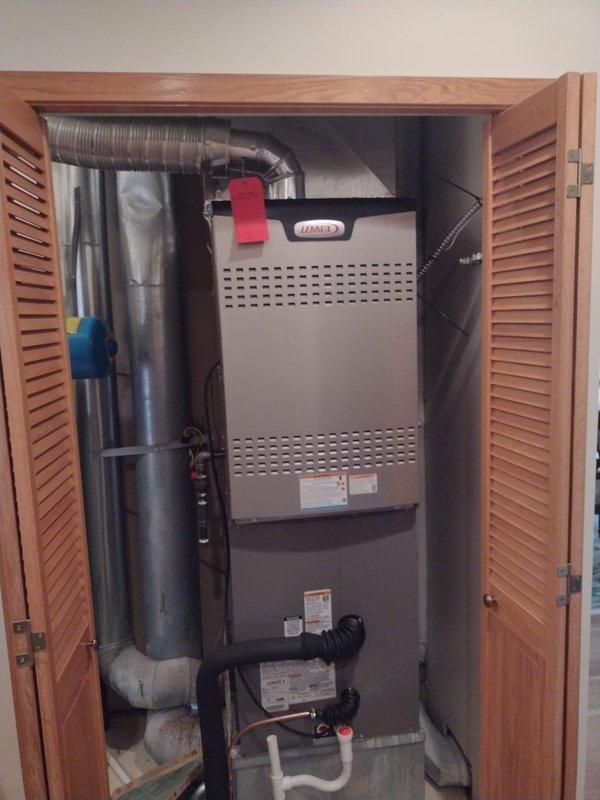 Completed full HVAC system installation including Lennox 80% efficiency downflow furnace with metallic supply ductwork and gray flexible return ducting, outdoor air conditioning condenser unit, and Lennox S40 smart thermostat. Installed 40-gallon Bradford White residential water heater with proper venting, copper supply lines, red-handled isolation valves, blue thermal expansion tank, and PVC condensate drainage system with pump. All equipment installed in dedicated utility closet with louvered door access, systems tested for proper operation, and installation meets manufacturer specifications and local code requirements.