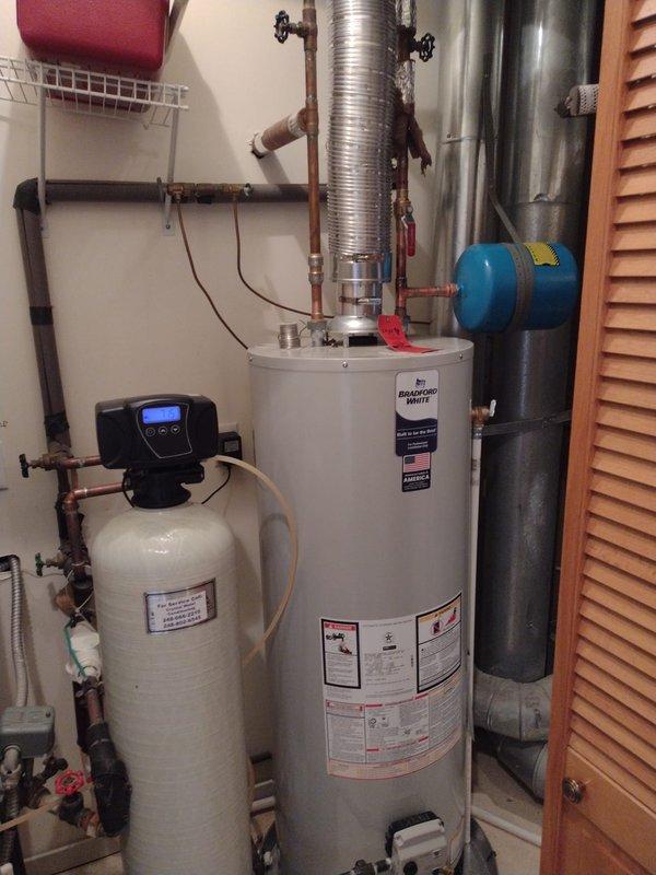 Completed full HVAC system installation including Lennox 80% efficiency downflow furnace with metallic supply ductwork and gray flexible return ducting, outdoor air conditioning condenser unit, and Lennox S40 smart thermostat. Installed 40-gallon Bradford White residential water heater with proper venting, copper supply lines, red-handled isolation valves, blue thermal expansion tank, and PVC condensate drainage system with pump. All equipment installed in dedicated utility closet with louvered door access, systems tested for proper operation, and installation meets manufacturer specifications and local code requirements.