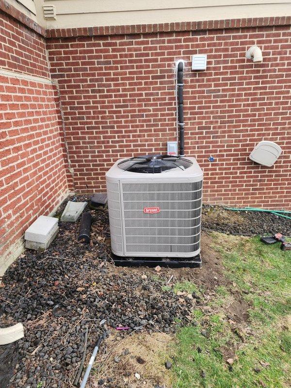 Successfully completed installation of Bryant air conditioning system and humidifier at residential property. Outdoor condensing unit was positioned on concrete pad against brick exterior wall with proper clearances maintained, including installation of electrical disconnect box and refrigerant line set routed through conduit. Indoor air handler was integrated with existing furnace system in basement utility area, with humidifier installed on supply plenum and all ductwork connections completed. System was charged with refrigerant, tested for proper operation across all components, and verified to meet manufacturer specifications.