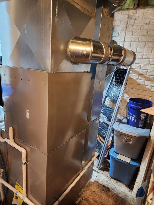 Successfully completed installation of Bryant air conditioning system and humidifier at residential property. Outdoor condensing unit was positioned on concrete pad against brick exterior wall with proper clearances maintained, including installation of electrical disconnect box and refrigerant line set routed through conduit. Indoor air handler was integrated with existing furnace system in basement utility area, with humidifier installed on supply plenum and all ductwork connections completed. System was charged with refrigerant, tested for proper operation across all components, and verified to meet manufacturer specifications.