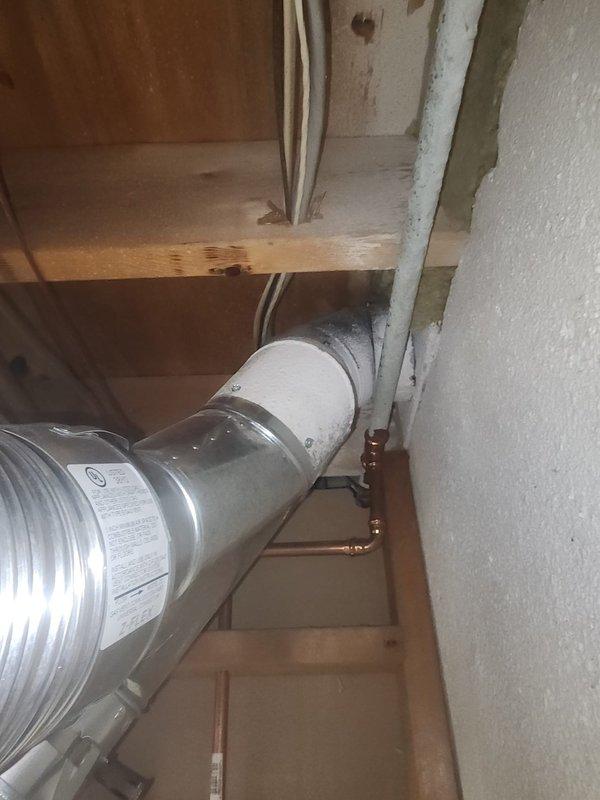 Responded to final inspection correction regarding furnace exhaust clearance violation at ceiling level. Single wall exhaust vent was found in close proximity to combustible materials including electrical wiring, failing to meet required 6-inch clearance code. Documented existing conditions with photos showing metal ductwork routing through floor joists near copper plumbing lines and electrical cables, confirming the clearance deficiency cited by inspector.