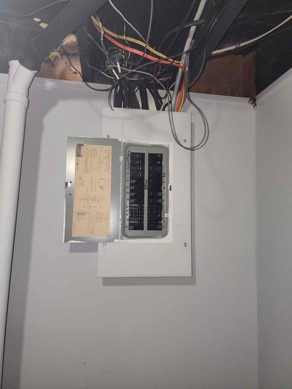 Completed electrical service upgrade from 60 amp to 200 amp panel in residential utility area. Existing panel showed outdated wiring configuration with multiple circuits requiring consolidation and proper organization of conductors entering from overhead junction. New 200 amp main breaker panel installed with updated circuit directory and proper wire management to meet current electrical code requirements.