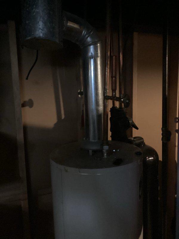 Conducted on-site evaluation and prepared detailed estimate for water heater replacement in residential basement utility area. Assessed existing white cylindrical tank water heater with atmospheric venting system, including inspection of metallic flue pipe, ductwork connections, and surrounding copper supply plumbing infrastructure. Documented current installation conditions, clearances, and access points for future replacement work. Photographed existing unit configuration, piping connections at tank base, and ventilation system routing to support accurate material specifications and labor requirements for upcoming installation.