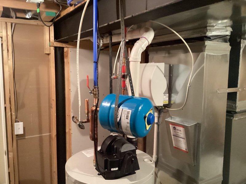 Installed 50-gallon tanked water heater in basement utility room to serve residential hot water needs for 1-3 occupants. Connected copper supply lines with shut-off valves, installed pressure relief valve with discharge piping, and integrated blue pressure tank with pump assembly to maintain consistent water pressure throughout the system. Verified all connections for proper operation and leak-free performance.