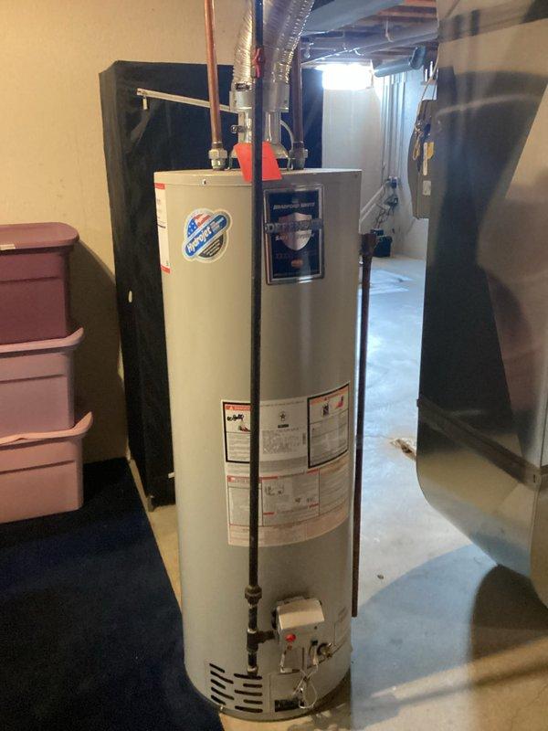 Conducted on-site assessment and provided detailed estimate for water heater replacement in basement utility area. Evaluated existing white cylindrical gas water heater, documented current installation including copper supply piping, gas valve assembly, and venting configuration. Photographed equipment specifications, manufacturer labels, and surrounding mechanical systems including adjacent HVAC unit and ductwork to ensure accurate replacement planning and proper clearance requirements for new installation.