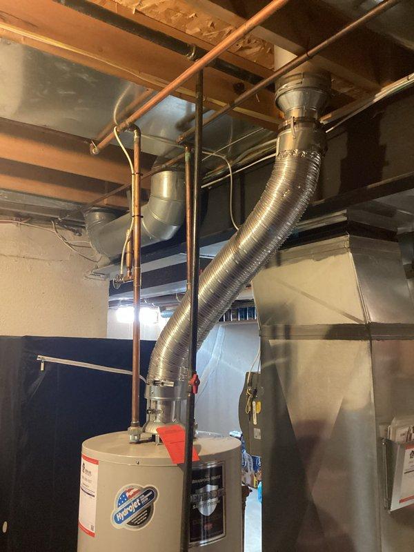 Conducted on-site assessment and provided detailed estimate for water heater replacement in basement utility area. Evaluated existing white cylindrical gas water heater, documented current installation including copper supply piping, gas valve assembly, and venting configuration. Photographed equipment specifications, manufacturer labels, and surrounding mechanical systems including adjacent HVAC unit and ductwork to ensure accurate replacement planning and proper clearance requirements for new installation.