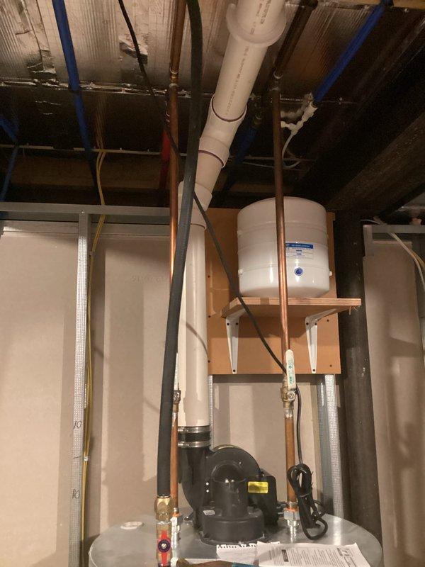 Conducted on-site assessment for tankless water heater installation in residential basement utility area. Evaluated existing plumbing infrastructure including copper supply lines, PVC drainage system, pressure tank configuration, and circulating pump setup to determine feasibility and requirements for converting from traditional tank system to tankless unit. Documented current mechanical room layout, overhead joist clearances, gas line accessibility, venting pathways through existing ductwork areas, and electrical service capacity for proper equipment specification and installation planning.