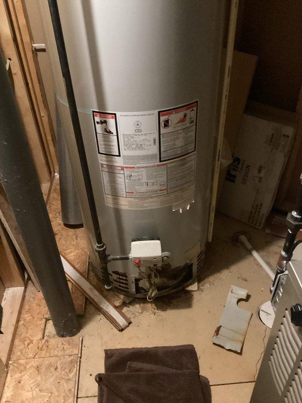 Responded to service call for non-functioning 17-year-old residential water heater that failed to ignite due to apparent corrosion damage. Conducted on-site assessment of gas-fired water heater installation in unfinished basement utility area. Inspected unit condition, verified corrosion at tank body, examined copper supply and distribution piping connections, gas line connections, temperature and pressure relief valve, and electrical/control components. Photographed existing installation showing water heater mounted on OSB platform with standard plumbing connections including cold water intake, hot water outlet, TPR valve discharge piping, and gas supply line. Documented surrounding plumbing infrastructure including vertical pipe runs and PVC venting system. Evaluated age-related deterioration and determined unit had reached end of serviceable life. Prepared comprehensive replacement estimate for new water heater installation including removal and disposal of failed unit, supply and i
