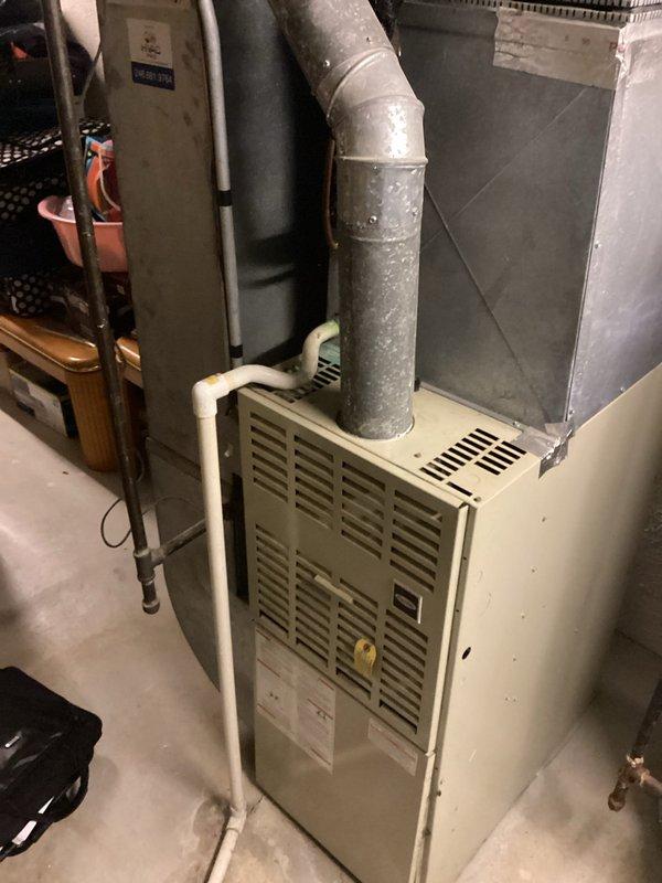 Completed comprehensive assessment of residential HVAC system featuring a 33-year-old furnace unit located in basement utility area. Documented existing equipment configuration including furnace, ductwork, PVC condensate drainage system, and associated components to provide detailed replacement estimate for aging heating system that has exceeded its expected service life.