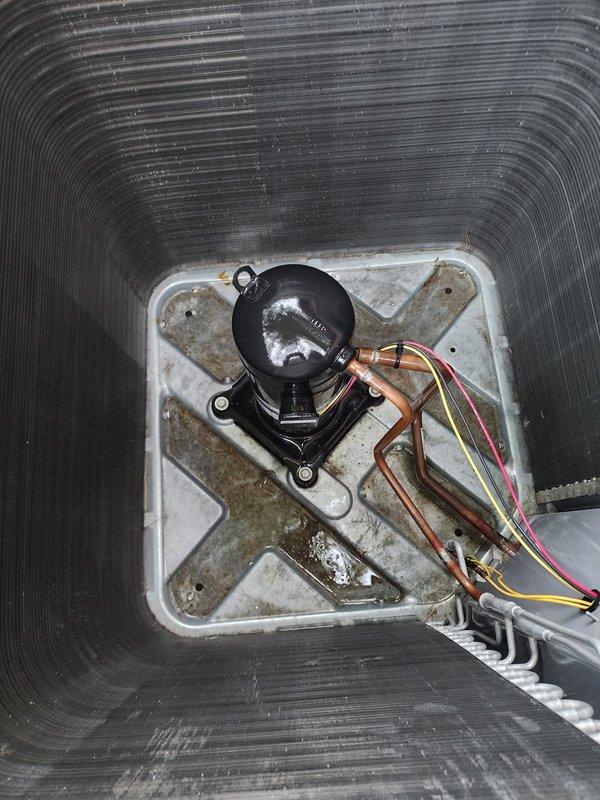 Completed scheduled air conditioning maintenance on outdoor condenser unit and associated indoor components. Performed visual inspection of exterior condenser, noting unit operational with normal wear consistent with age. Verified condenser pad level and stable on concrete foundation. Inspected electrical connections and refrigerant line sets running to building exterior. Accessed indoor air handler, inspecting condensate drain pan and pump assembly. Observed mineral deposits and staining on drain pan indicating normal condensation activity. Verified condensate pump mounting secure and drain lines properly connected. All system components found operational during maintenance inspection.