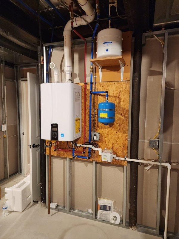 Completed installation of Energy Star certified tankless water heater system in basement utility area. Mounted unit on OSB backing with proper structural support, connected white PVC venting through ceiling, and installed blue PEX cold water supply line and copper hot water distribution lines. Integrated blue expansion tank to wall mounting system and verified all plumbing connections, valves, and fittings for proper operation. System tested and operational upon completion.