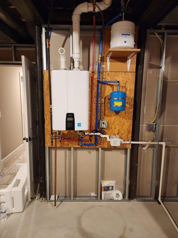 Completed installation of Energy Star certified tankless water heater system in basement utility area. Mounted unit on OSB backing with proper structural support, connected white PVC venting through ceiling, and installed blue PEX cold water supply line and copper hot water distribution lines. Integrated blue expansion tank to wall mounting system and verified all plumbing connections, valves, and fittings for proper operation. System tested and operational upon completion.