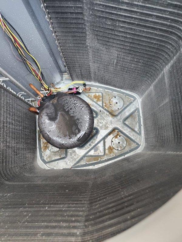 # HVAC Maintenance - Cooling System Service

Completed scheduled air conditioning maintenance on residential cooling system during evening appointment window. Performed comprehensive inspection of outdoor condenser unit, which showed significant accumulation of dirt and debris on heat exchanger coil fins with visible darkening and dust buildup affecting airflow efficiency. Condenser cabinet and frame were in serviceable condition with normal weathering for outdoor exposure.

Accessed indoor air handler unit and inspected evaporator coil section and drain pan assembly. Found condensate drain pan with moderate mineral deposits and water staining around drain fitting, indicating active moisture management but requiring attention to prevent future blockages. Drain line and condensate removal system were operational with proper drainage observed. Inspected electrical connections and refrigerant line connections at air handler, which appeared secure with appropriate insulation intact.

Syste