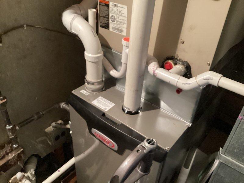 Responded to callback for exhaust intake repair on roof. Upon inspection, found two PVC vent pipe assemblies protruding from rooftop with black rubber boot seals—one shorter assembly with white cap and one taller assembly with beige middle section between white PVC segments. Verified proper sealing at roof penetrations and confirmed HVAC system operation, including furnace/air handler unit with connected ductwork and PVC condensate/vent lines. All components functioning properly with no leaks detected at roof penetrations or indoor connections.