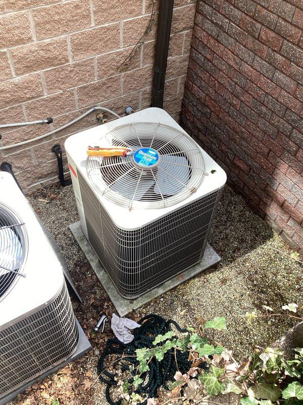 Responded to request for AC replacement estimate. Inspected two existing outdoor condenser units positioned against exterior brick walls, documented current equipment condition including refrigerant line connections, electrical conduits, and mounting configurations on concrete pads for replacement proposal.