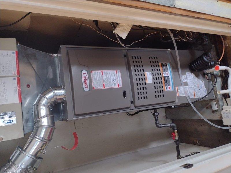 Completed full HVAC system installation including Lennox 80% efficiency downflow furnace mounted horizontally in attic space between floor joists and matching air conditioning condenser unit positioned on exterior concrete pad against brick wall. Installed all necessary refrigerant lines, condensate drain piping, flexible ductwork connections, electrical wiring, and proper mounting hardware per manufacturer specifications. System tested and operational upon completion.