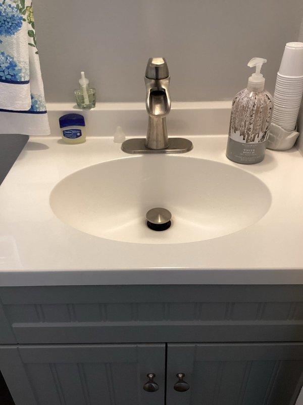 Responded to water hammer issue in half bath plumbing system that was causing water to shoot into kitchen when fixtures were used. Inspected under-sink plumbing connections and drainage assembly in main floor half bath, verifying proper installation of PVC drain lines, supply connections, and fixture mounting. Documented existing plumbing configuration with photos showing vanity sink assembly, faucet installation, and under-counter plumbing connections to assist with diagnosing the intermittent pressure surge problem that has persisted since water heater replacement six months prior.