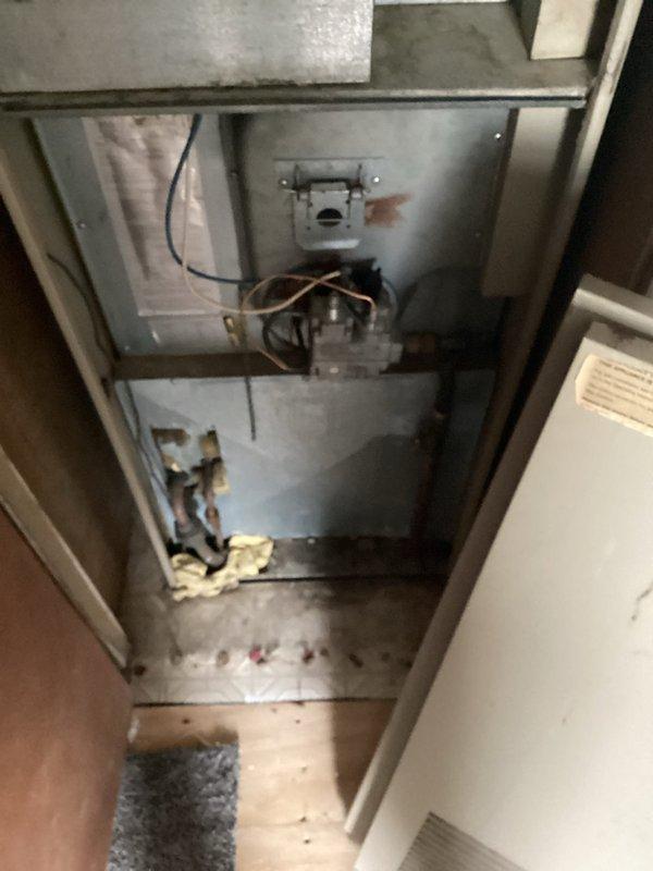 Conducted comprehensive HVAC system evaluation for new homeowner reporting cracked heat exchanger and complete air conditioning failure. Inspected vertical furnace/air handler unit installed in residential closet configuration, documented burner assembly, gas connections, and internal components to assess equipment condition and determine replacement requirements.