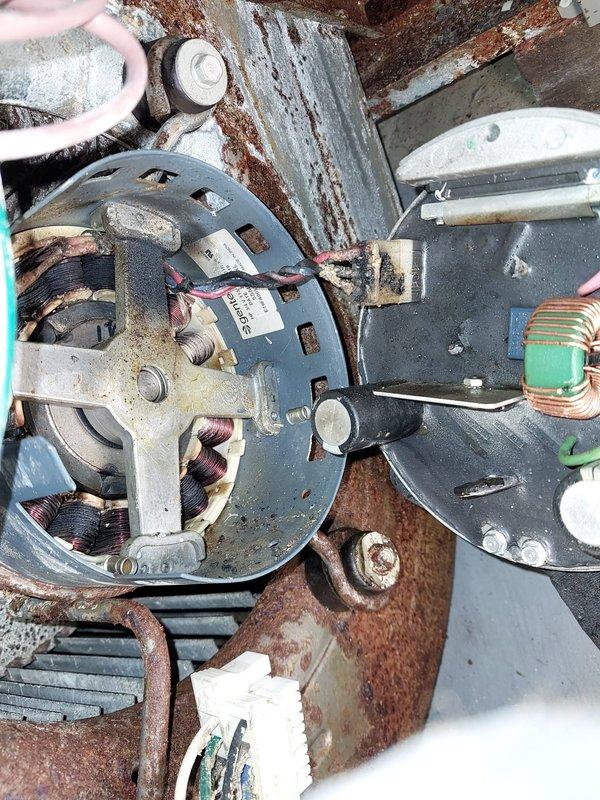 Responded to no-heat call on five-year-old furnace that had been powered off due to burning smell following water exposure in basement. Upon inspection, discovered extensive rust and corrosion throughout the blower assembly, motor mounting bracket, and surrounding metal components, indicating significant moisture intrusion. The induced draft motor, blower motor, and electrical connections showed heavy deterioration with rust covering mounting plates, brackets, and metal housing. Water damage had compromised the structural integrity of multiple components, with corrosion patterns suggesting prolonged exposure or substantial water event. 

Documented the condition of all affected components with photographs showing rust-covered motor assemblies, deteriorated mounting hardware, and compromised electrical connections. The blower motor housing exhibited severe rust penetration on the circular mounting plate and support structures. Wiring connections showed signs of moisture exposure with vi