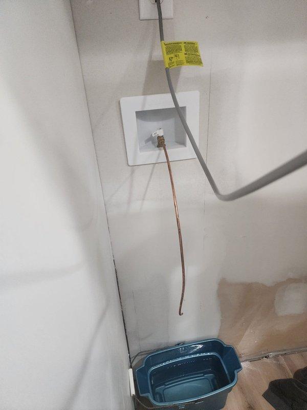 Responded to callback regarding hot water issue from refrigerator. Upon inspection, examined refrigerant lines, compressor unit, and associated plumbing connections. Verified proper installation of drain pan beneath equipment and documented current system configuration with copper tubing, flexible conduit, and wall-mounted outlet box. All components photographed for service records.