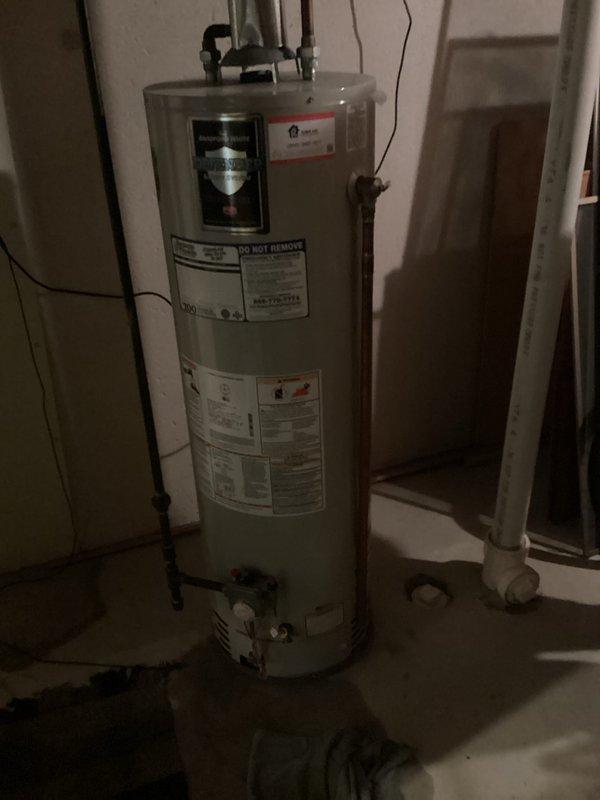 Performed on-site assessment of existing gas-fired water heater located in basement utility area. Documented current installation including copper supply lines with shutoff valve, temperature and pressure relief valve configuration, gas control assembly, and venting system with PVC exhaust piping. Evaluated unit age, condition, and operational status to provide replacement estimate. Photographed existing water heater installation showing manufacturer specifications, plumbing connections, gas line routing, and surrounding mechanical equipment including adjacent water treatment system. Assessed accessibility for replacement work and identified installation requirements for new unit.