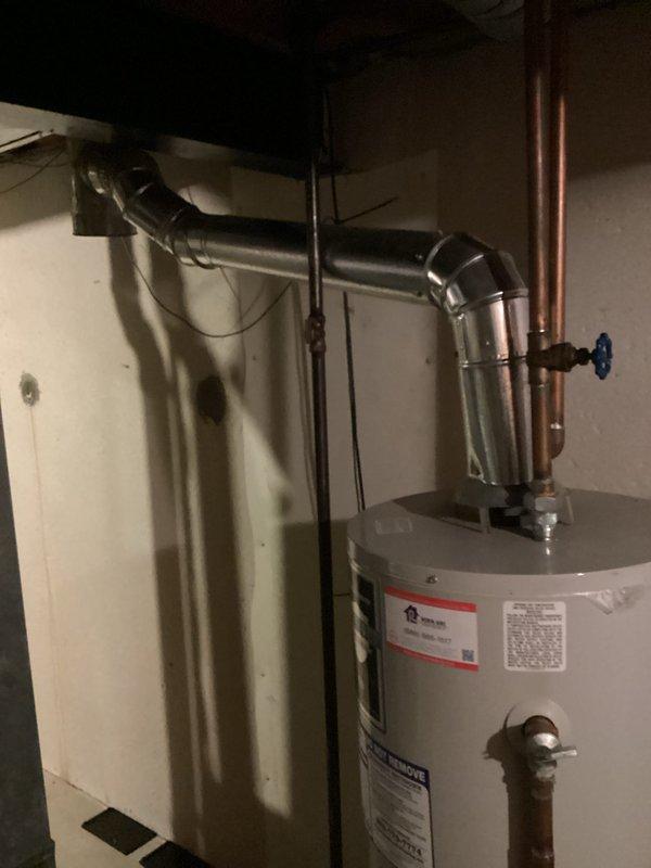 Performed on-site assessment of existing gas-fired water heater located in basement utility area. Documented current installation including copper supply lines with shutoff valve, temperature and pressure relief valve configuration, gas control assembly, and venting system with PVC exhaust piping. Evaluated unit age, condition, and operational status to provide replacement estimate. Photographed existing water heater installation showing manufacturer specifications, plumbing connections, gas line routing, and surrounding mechanical equipment including adjacent water treatment system. Assessed accessibility for replacement work and identified installation requirements for new unit.