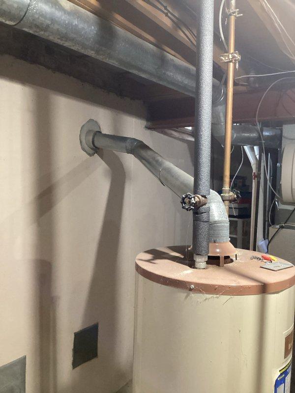 Provided estimate for replacement of 40-year-old residential water heater located in basement utility area. Unit is currently leaking and requires replacement. Assessed existing installation including venting configuration, water supply connections, and available space for new equipment installation in unfinished basement setting with exposed ceiling joists.