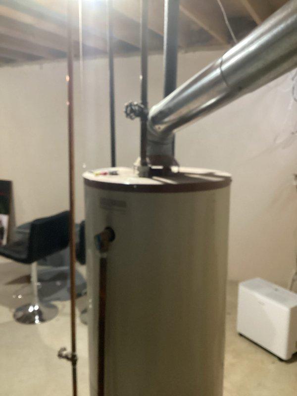 Provided estimate for replacement of 40-year-old residential water heater located in basement utility area. Unit is currently leaking and requires replacement. Assessed existing installation including venting configuration, water supply connections, and available space for new equipment installation in unfinished basement setting with exposed ceiling joists.