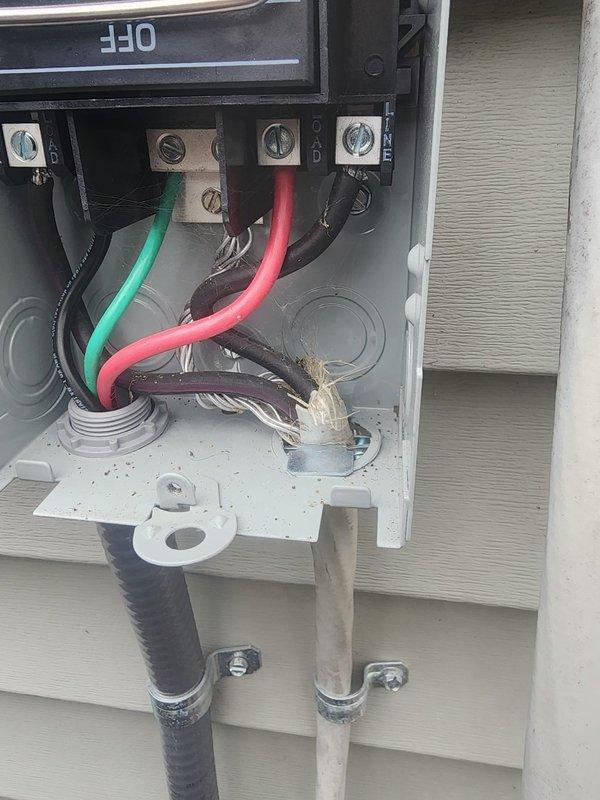 Responded to failed inspection callback to address unprotected service cable wiring at outdoor disconnect box. Upon arrival, found existing installation with black flexible conduit lacking proper connector at disconnect entry point. Installed appropriate weatherproof connector on service cable to secure and protect wiring entering the disconnect box per code requirements. Verified all electrical connections at terminal block were tight and secure, with proper wire terminations on green ground, red, and black conductors. Ensured conduit straps were properly fastened to wall and mounting plate. Installation now meets electrical code standards for exterior disconnect protection and passed re-inspection criteria.