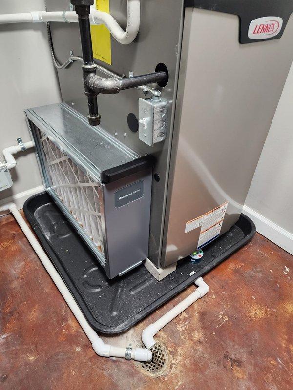 Completed full HVAC system installation including Lennox furnace, air conditioning unit, and S40 smart thermostat in residential utility room. Installed furnace on protective drain pan with proper PVC venting configuration, integrated air filtration cabinet with pleated filter assembly, and connected all necessary ductwork including flexible metallic and insulated black piping. Mounted thermostat, ran electrical connections, sealed all roof penetrations from screw and nail holes per specifications, verified proper drainage, and tested system operation to ensure full functionality.