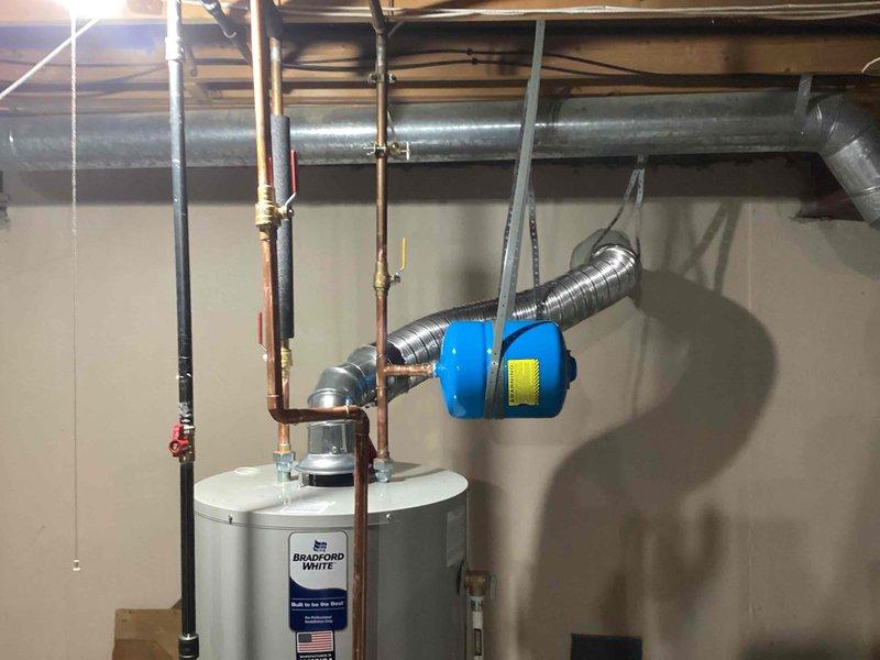 Successfully installed a 50-gallon Bradford White tanked water heater in the basement utility area. The installation included complete copper piping connections with brass fittings, proper venting through flexible metallic ductwork, and integration of a thermal expansion tank to protect the system from pressure fluctuations. All plumbing connections were secured with appropriate valving and supports, and the unit was tested for proper operation upon completion.