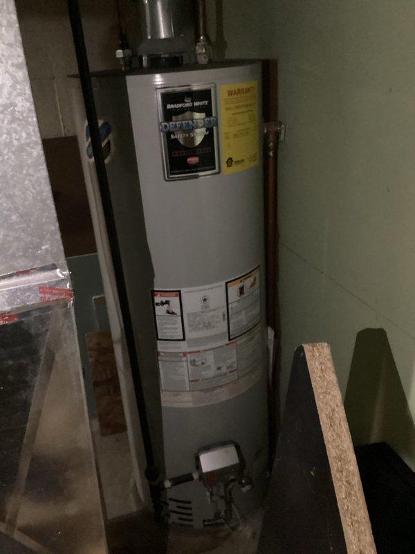 Completed estimate for residential water heater replacement in basement utility area. Assessed existing Bradford White Defender Safety System water heater with gas control valve assembly and evaluated current venting configuration including galvanized metal vent pipe with 90-degree bend. Documented copper supply piping, shut-off valves, and mounting brackets for replacement specifications.