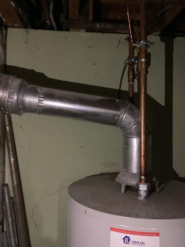 Completed estimate for residential water heater replacement in basement utility area. Assessed existing Bradford White Defender Safety System water heater with gas control valve assembly and evaluated current venting configuration including galvanized metal vent pipe with 90-degree bend. Documented copper supply piping, shut-off valves, and mounting brackets for replacement specifications.