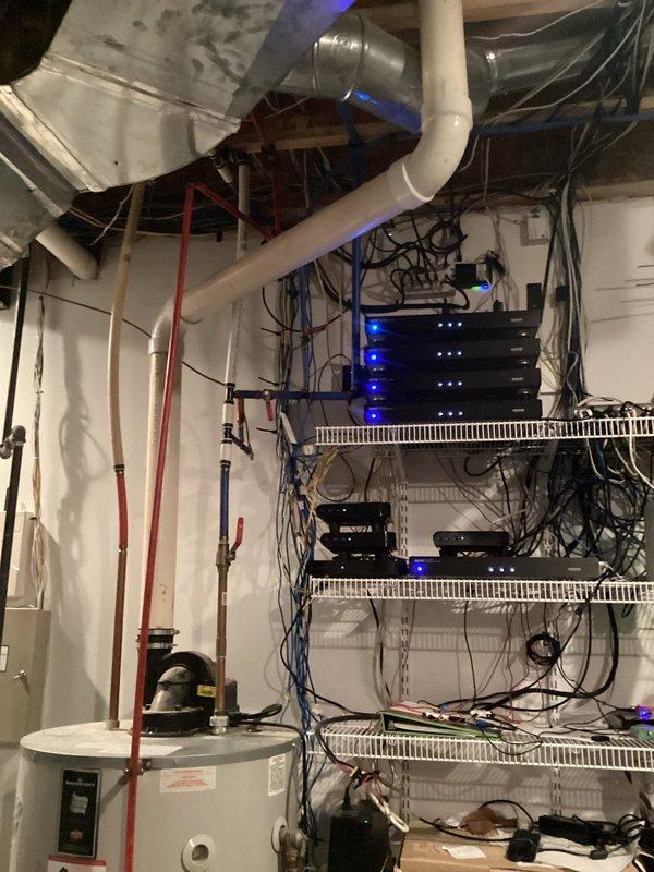 Responded to report of leaking water heater in mechanical room. Performed on-site assessment of existing white cylindrical tank-style water heater with connected copper piping, red supply lines, and mounted circulation pump. Documented current installation configuration including proximity to networking equipment and storage areas in unfinished basement space. Provided comprehensive estimate for water heater replacement due to tank failure, including removal of existing unit, installation of new water heater with proper venting and code-compliant connections, and disposal of failed equipment.