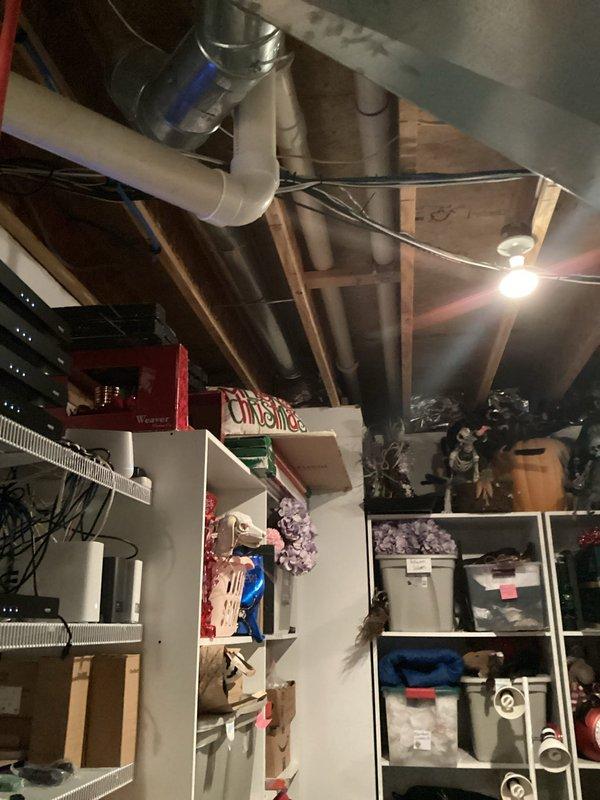 Responded to report of leaking water heater in mechanical room. Performed on-site assessment of existing white cylindrical tank-style water heater with connected copper piping, red supply lines, and mounted circulation pump. Documented current installation configuration including proximity to networking equipment and storage areas in unfinished basement space. Provided comprehensive estimate for water heater replacement due to tank failure, including removal of existing unit, installation of new water heater with proper venting and code-compliant connections, and disposal of failed equipment.