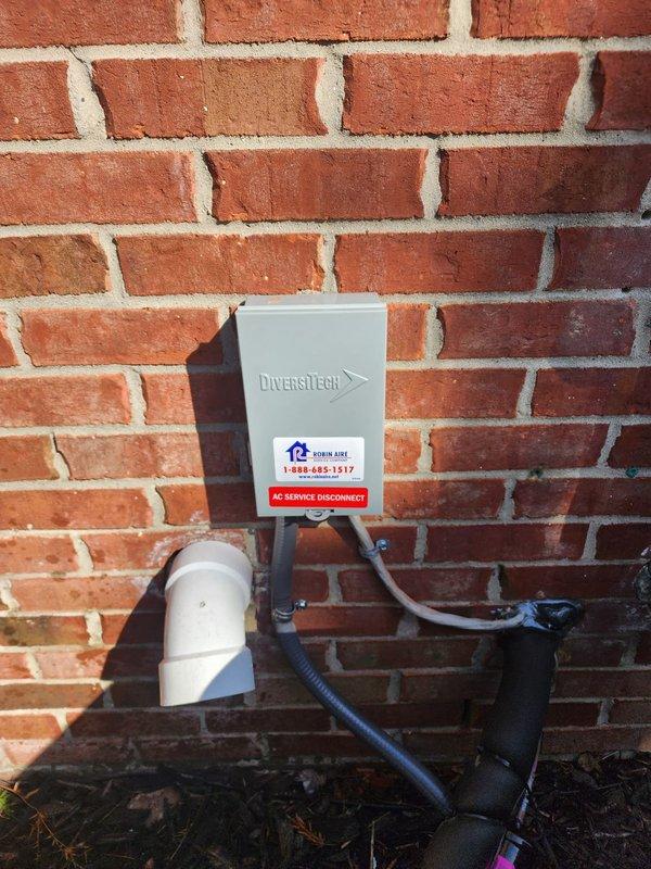 Completed installation of Bryant air conditioning system at residential property. Mounted condensing unit on exterior pad against brick foundation with proper clearances for airflow and serviceability. Installed Diversitech electrical disconnect box on exterior wall with appropriate conduit routing and secured all electrical connections per manufacturer specifications and local code requirements. Ran condensate drain line using white PVC piping with proper pitch for drainage. Applied service identification labels to disconnect box for future reference. Verified system startup, refrigerant charge, and operational parameters. Unit tested and confirmed cooling operation within normal range.