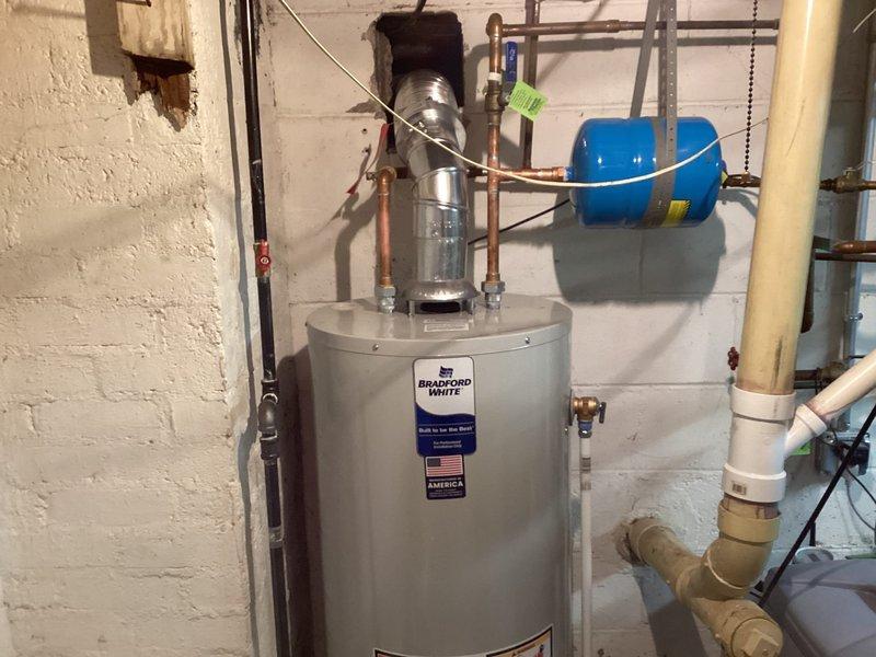 Completed installation of a 40-gallon Bradford White tanked water heater in basement utility area. Established all necessary water supply connections using copper piping, installed expansion tank at top of unit, and connected discharge piping per code requirements. Verified proper operation of all components, tested temperature and pressure relief valve functionality, and confirmed system is operating safely within manufacturer specifications.