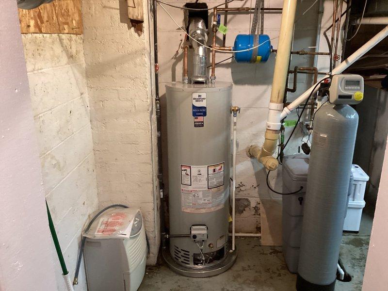 Completed installation of a 40-gallon Bradford White tanked water heater in basement utility area. Established all necessary water supply connections using copper piping, installed expansion tank at top of unit, and connected discharge piping per code requirements. Verified proper operation of all components, tested temperature and pressure relief valve functionality, and confirmed system is operating safely within manufacturer specifications.
