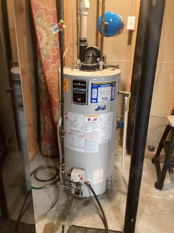 Completed on-site assessment and provided replacement estimate for existing white cylindrical water heater located in basement utility area. Evaluated current unit positioned between wall studs with copper supply piping, pressure relief valve assembly, and electrical connection. Documented existing plumbing configuration including blue expansion tank, well pump system, and associated PVC piping network to ensure accurate replacement specifications and proper integration with current mechanical systems.