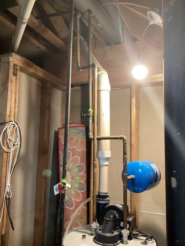 Completed on-site assessment and provided replacement estimate for existing white cylindrical water heater located in basement utility area. Evaluated current unit positioned between wall studs with copper supply piping, pressure relief valve assembly, and electrical connection. Documented existing plumbing configuration including blue expansion tank, well pump system, and associated PVC piping network to ensure accurate replacement specifications and proper integration with current mechanical systems.