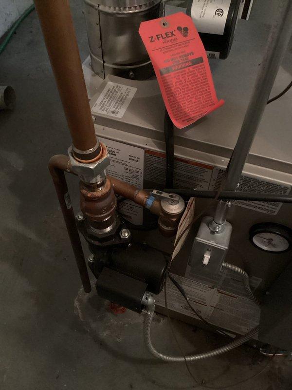 Responded to service call for boiler leaking water. Upon inspection, identified active leak in heating system piping connections. Examined circulator pump assembly and associated copper piping showing oxidation and age-related wear. Tightened compromised fittings and connections where seepage was occurring. Verified system pressure gauge readings and monitored digital temperature display showing 43°F. Tested system operation after repairs to confirm leak was resolved and all connections were secure with no further water discharge.