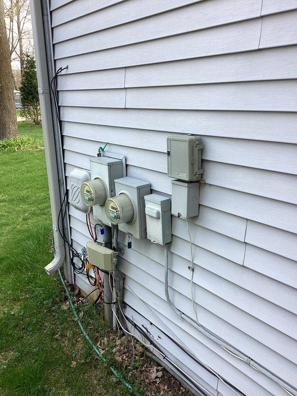Conducted on-site evaluation for replacement of 32-year-old residential air conditioning system located on side of single-family, owner-occupied home. Assessed existing outdoor condensing unit placement, electrical service connections including dual meter configuration and associated disconnect boxes, and indoor air handler integration with existing furnace and ductwork system. Documented current equipment condition, electrical infrastructure, and HVAC system layout including galvanized and flexible duct connections, PVC condensate piping, and basement installation configuration to provide comprehensive replacement estimate for new AC unit installation.