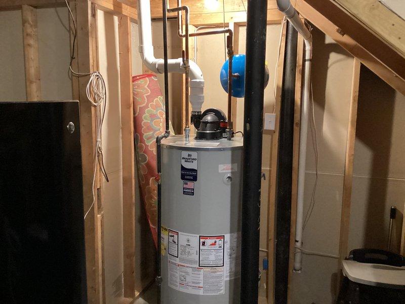 Completed installation of a 75-gallon tanked water heater in unfinished basement utility area. Connected all necessary copper supply lines and PVC piping, installed circulation pump with proper mounting and hose clamps, and integrated blue expansion tank to system for proper pressure regulation. All components installed per manufacturer specifications with appropriate Teflon tape application, venting assembly secured, and system tested for proper operation and leak-free connections.