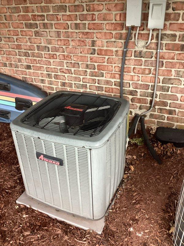 Responded to service call for non-cooling air conditioning system at single-family residence. Evaluated existing 15+ year old 3-ton Amana condenser unit located in backyard beneath deck structure on concrete pad. Unit positioned against brick wall with electrical disconnect and line set protection visible. Documented equipment condition and installation setup including secondary HVAC unit adjacent to primary system. Prepared replacement estimate for aging air conditioning system per homeowner request. Captured photographic documentation of existing equipment, electrical connections, condensate drain lines, and surrounding installation area for quote preparation purposes.