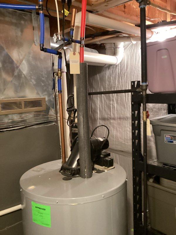 Conducted on-site assessment of 10-year-old PowerFlex residential water heater experiencing active leakage in basement utility area. Documented existing unit configuration including PVC discharge piping, pressure relief valve assembly, and standard plumbing connections. Photographed installation conditions, surrounding mechanical systems, and evidence of water accumulation at base to provide comprehensive estimate for complete water heater replacement.