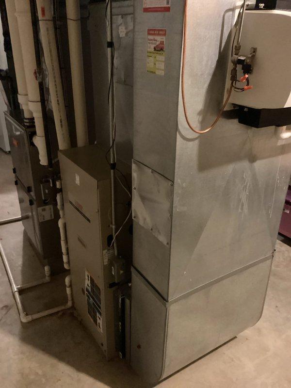 Conducted comprehensive on-site evaluation of existing HVAC system in basement utility area for R-22 refrigerant-based air conditioning replacement estimate. Assessed current furnace, air handler configuration, and associated ductwork connections, documenting equipment age, condition, and installation specifications. Photographed existing beige furnace unit with adjacent HVAC components, white PVC condensate drainage system, water heater proximity, and available workspace for potential equipment replacement, noting concrete floor installation area and electrical service accessibility for future system upgrade recommendations.