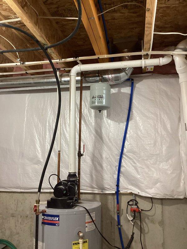 Completed water heater estimate for replacement of existing PowerFlex unit in basement utility area. Assessed current installation including pump assembly, copper supply lines, PVC drainage system, and blue PEX distribution piping. Documented existing configuration with concrete floor placement, electrical connections, and plumbing infrastructure routing through ceiling joists to prepare comprehensive replacement proposal.